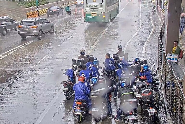 Motorcycle riders seeking shelter under overpass due to rain in EDSA