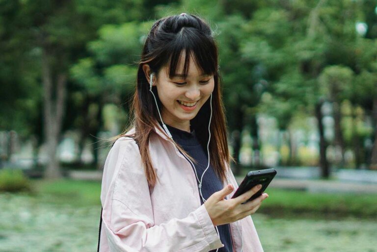 Young asian woman smiling at smartphone